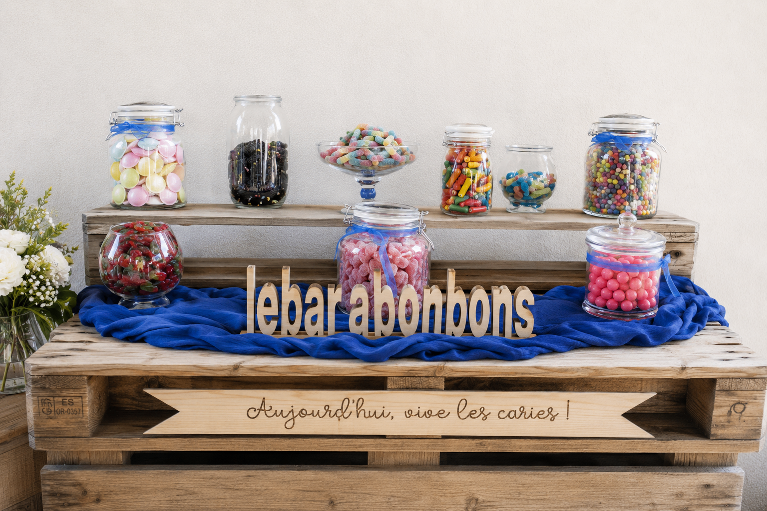 Bar à bonbons en bois de palette avec bonbonnières colorées et tissu bleu